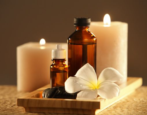 essential oils on a tray with candles and a flower